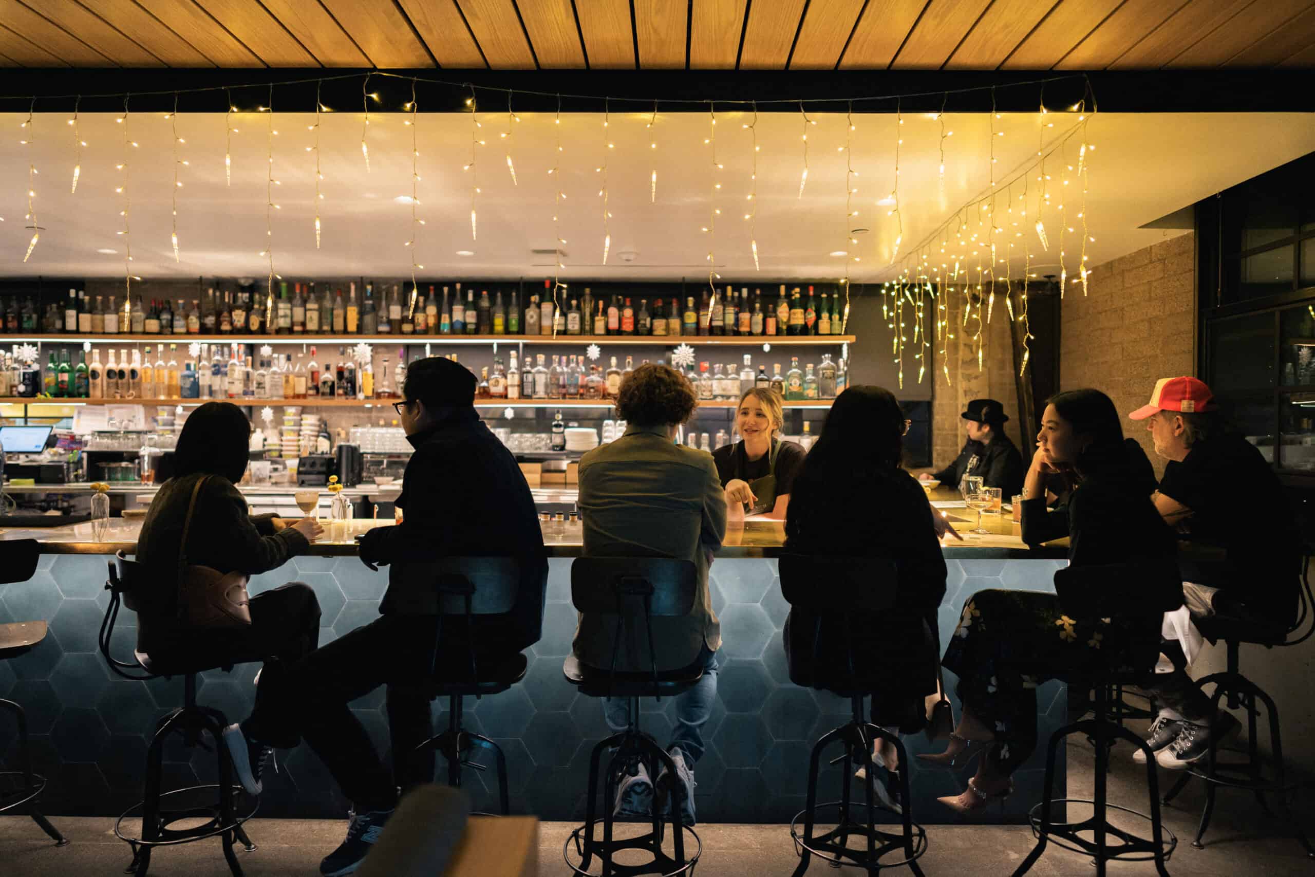 bar full of guests with twinkle lights dangling from the ceiling