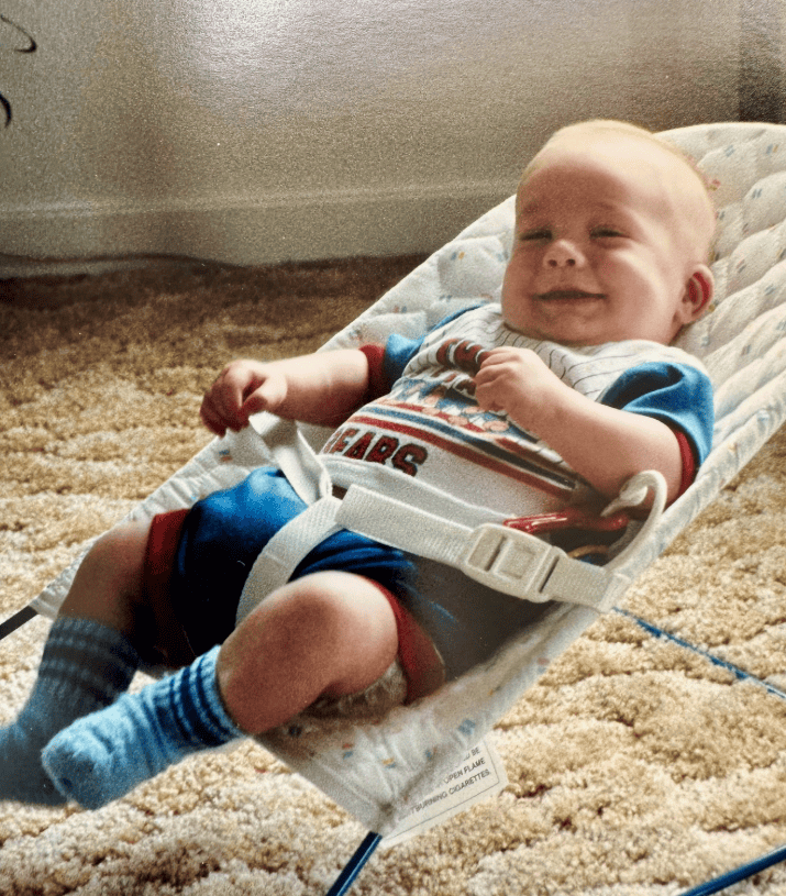 childhood photo of Chef Alex smiling in a baby chair