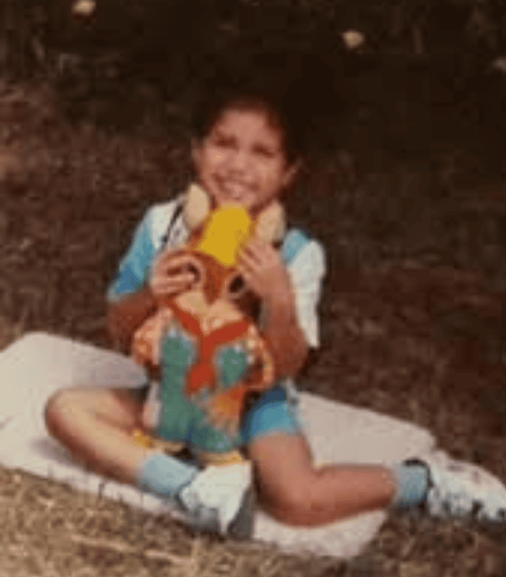 childhood photo of Chef Robert smiling with a stuffed animal